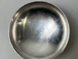 a small silver bowl on a white surface