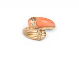 two gold rings with coral and diamonds on a white background