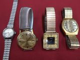 trois montres et un bracelet de montre sont posés sur une surface rouge