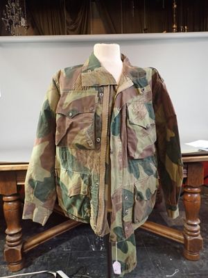 camouflage jacket sitting on a table next to a laptop computer