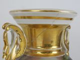 a gold vase with a painting on it sitting on a table