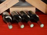 several bottles of wine sit in a wooden box on a red table cloth