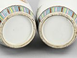 two white vases with colorful designs on them sitting side by side