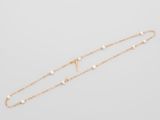 a gold chain bracelet with pearls and a cross on it