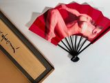 a picture of a woman on a red fan next to a box