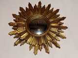 a gold sunburst hanging on the wall above a mirror