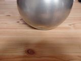 a silver vase sitting on a wooden table with a cat in the background