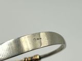 a close up of a silver bracelet with a gold clasp