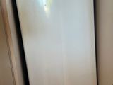 a white refrigerator in the corner of a small room