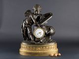 une statue représentant un garçon avec une horloge posée sur une table