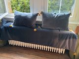un canapé sur lequel sont posés deux coussins, devant une fenêtre