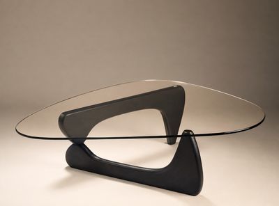 an image of a glass table with a black base and a curved glass top