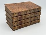 several old books stacked on top of each other on a white surface