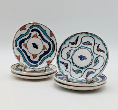 two plates with blue and orange designs on them sitting on a white surface
