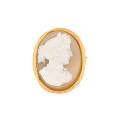 Une broche plaquée or représente le profil d'une femme.