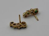 two pairs of gold earrings with emerald stones on them