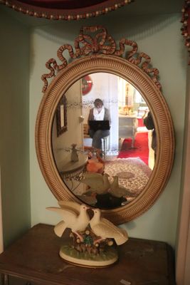 a small table with a mirror on it and a bird figurine on top of it
