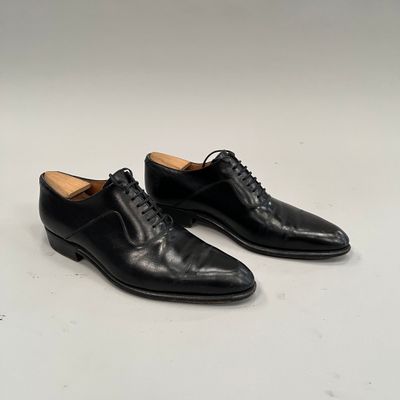 une paire de chaussures en cuir noir à lacets posées sur un fond blanc