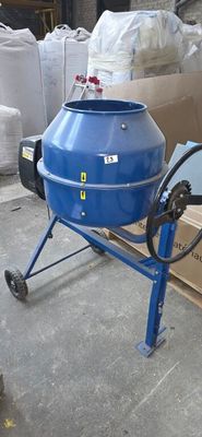 a blue cement mixer sitting on a cart in front of a pile of bags