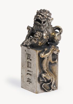 silver figurine of a lion on a block with chinese writing on it