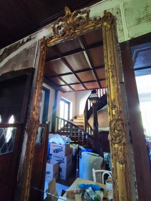 un miroir au milieu d'une pièce, avec un escalier en arrière-plan