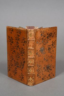an old book with a brown cover sitting on top of a table
