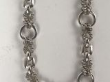 a close up of a silver chain necklace on a white surface
