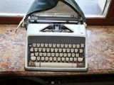 une vieille machine à écrire posée sur une table près d'une fenêtre