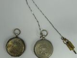 two silver pocket watches and a key on a white surface