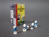 toy figurines of a group of smurfs with a box of books in the background