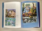 an open book with a picture of a house and a river