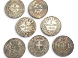 six silver coins of different shapes and sizes on a white surface