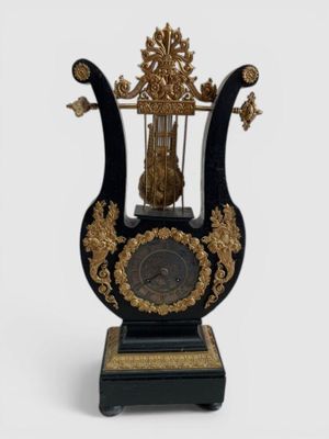 a black and gold clock with a bird cage on top