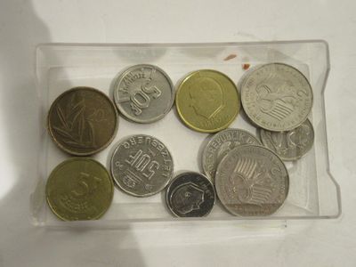 de nombreuses pièces de monnaie différentes dans un récipient en plastique posé sur une table