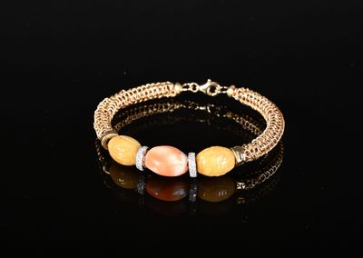 un bracelet plaqué or orné de perles orange et blanches sur un fond noir