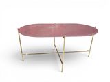 une table basse ovale rose aux pieds dorés sur fond blanc