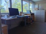 un ordinateur posé sur un bureau dans une pièce dotée d'une grande fenêtre