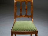 an antique wooden chair with green upholstered seat on a grey background
