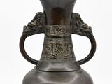 un vase en bronze muni d'une anse, sur fond blanc