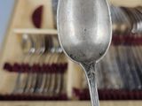 a silver spoon with a spoon rest in front of a rack of silver spoons