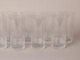 six glasses are lined up in a row on a white surface