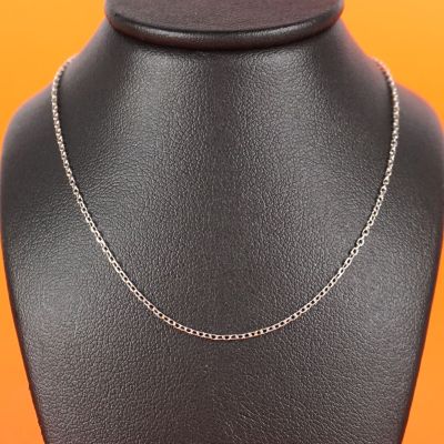 a silver necklace on a mannequin neck with an orange background