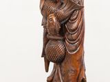 a wooden statue of a man holding a bird on his arm