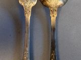 two silver spoons and a fork on a table