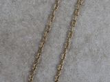 a close up of a necklace with a gold chain on a white surface