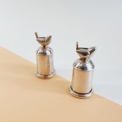 two silver pepper grinds sitting on top of a table