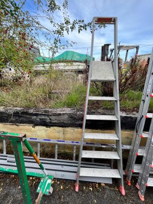 several ladders are stacked up next to each other on the side of a road