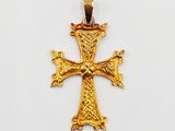 pendentif en forme de croix dorée sur fond blanc, avec un fond blanc