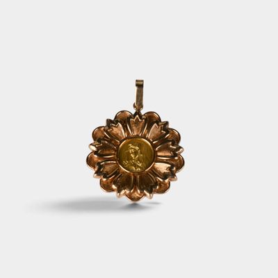 un gros plan d'un pendentif en forme de fleur dorée sur fond blanc