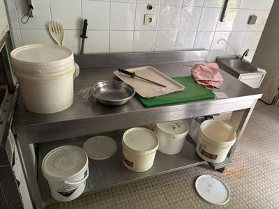 des casseroles et des poêles sont posées sur un plan de travail en acier inoxydable dans une cuisine